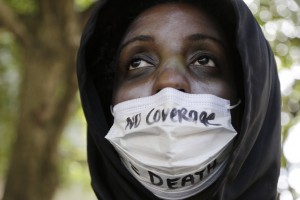 Kamalah Fletcher wears a medical mask over her face saying "No Coverage = Death" during a protest in support of Florida lawmakers expanding the eligibility criteria for Medicaid as called for under the Affordable Care Act in Miami. (AP Photo/Lynne Sladky)
