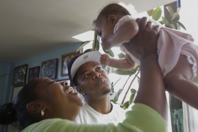 In this Aug. 25, 2014, photo, Nicole Randolph, left, and her brother Jonathan Miller, center, play with Miller's daughter in their uncle's apartment in New York. (AP Photo/Rachelle Blidner)