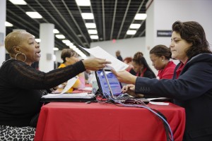 Homeowner Helena Platt, left, hands paperwork to Bank of America associate Mirella Gonzalez in an attempt to lower her monthly mortgage payment at a mortgage relief event by the Neighborhood Association Corporation of America, in Atlanta. (AP Photo/David Goldman, File)