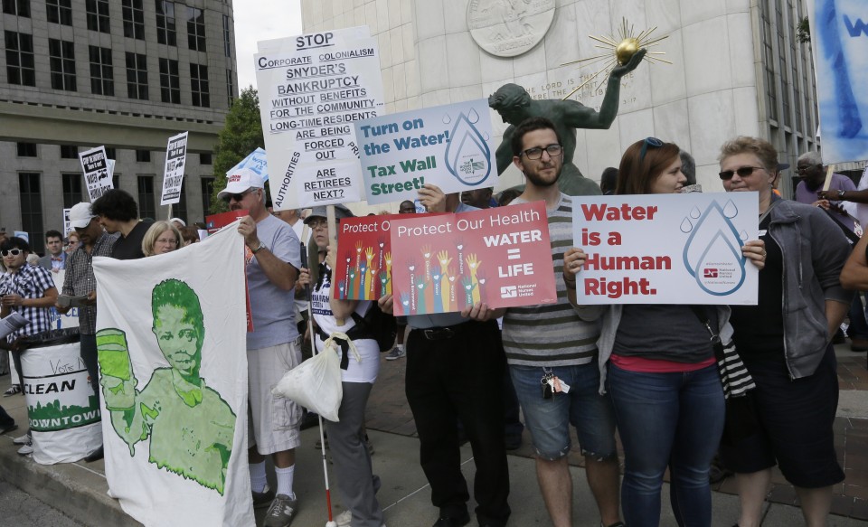 People stand outside Detroit City Hall, protesting thousands of residential water-service shutoffs by Detroit's water department, during a rally in Detroit, Thursday, July 24, 2014. (AP Photo)