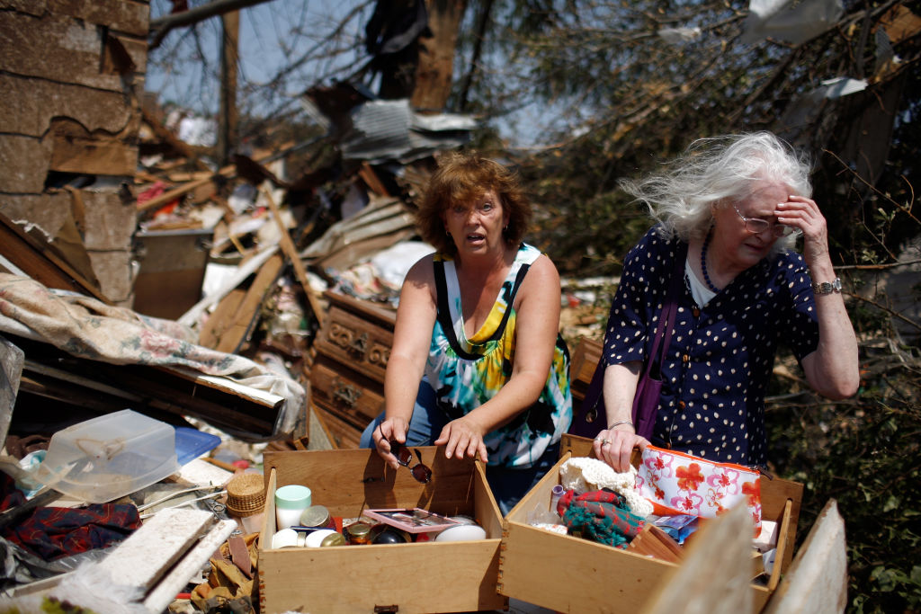 Two women sorting belongings at a tornado-damaged home