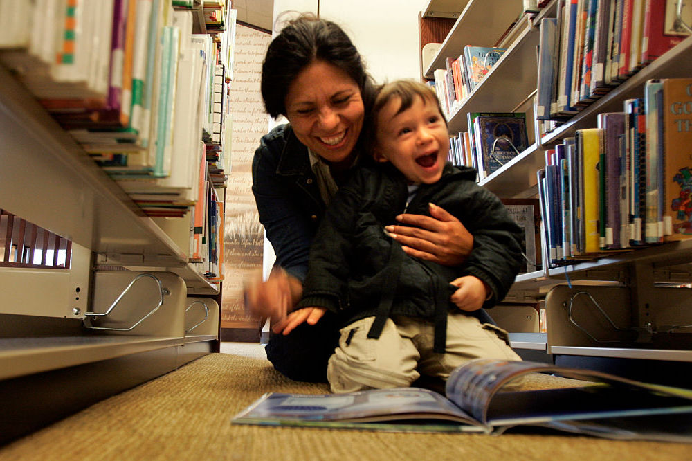 a woman reading a book to a laughing child