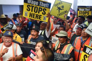 picketing workers with signs about wage theft