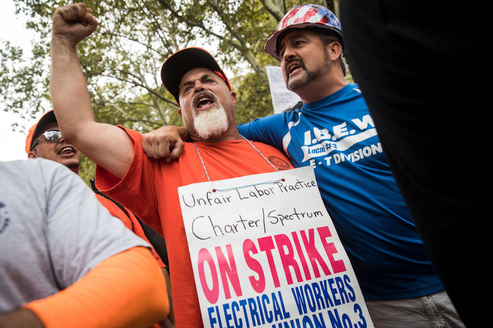 IBEW workers holding strike signage.