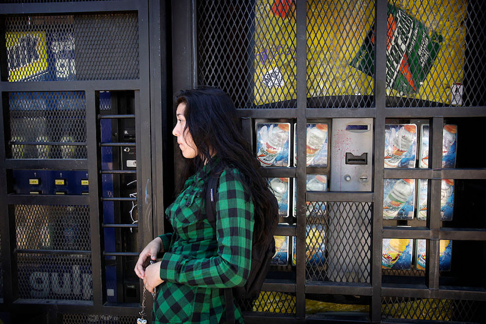 a student in green flannel leaning on a vending machine