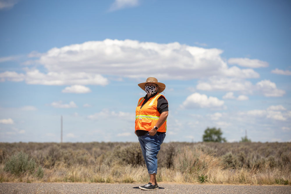 a woman in an orange safety vest standing in a road