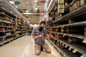 an instacart shopper kneeling to do a price check in a grocery store