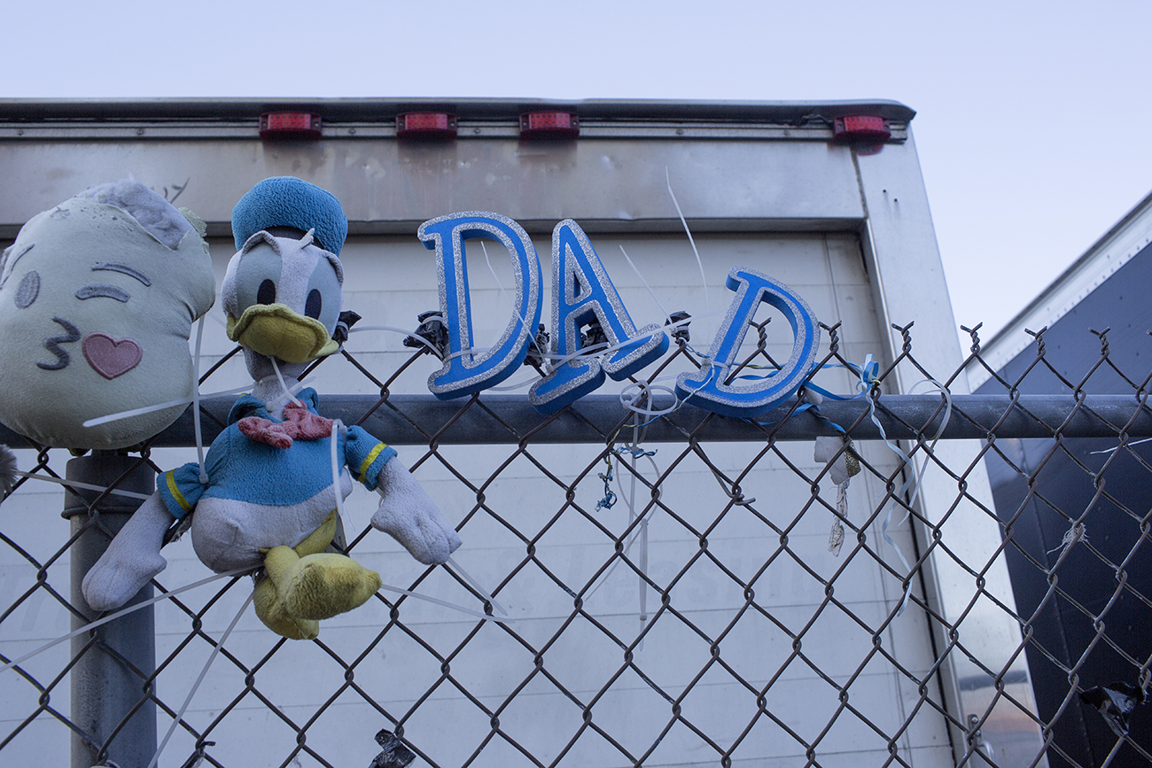 A Donald Duck stuffed animals and glittery letters spelling out "DAD" are tied to the fence outside of a prison